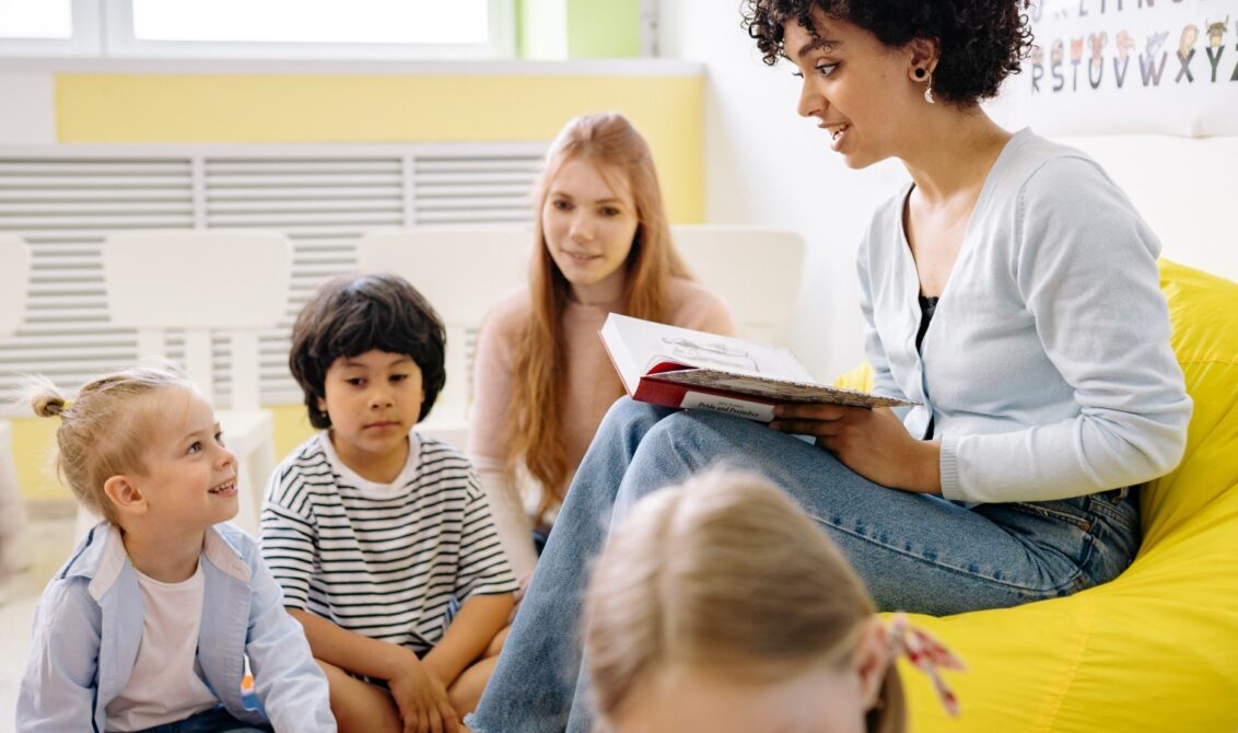 Woman reading a book to early years children